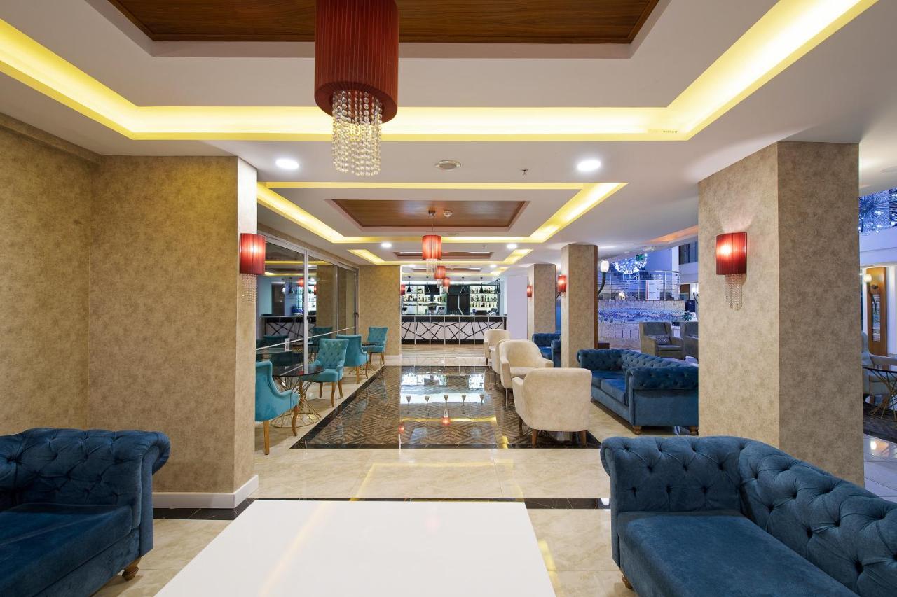 Sealife Family Resort Hotel Antalya Luaran gambar The photo depicts a modern and stylish lobby area. It features a combination of elegant furnishings, including blue and cream-colored sofas arranged around white tables. The floor has a shiny, dark tile that contrasts with the light-colored walls. Am