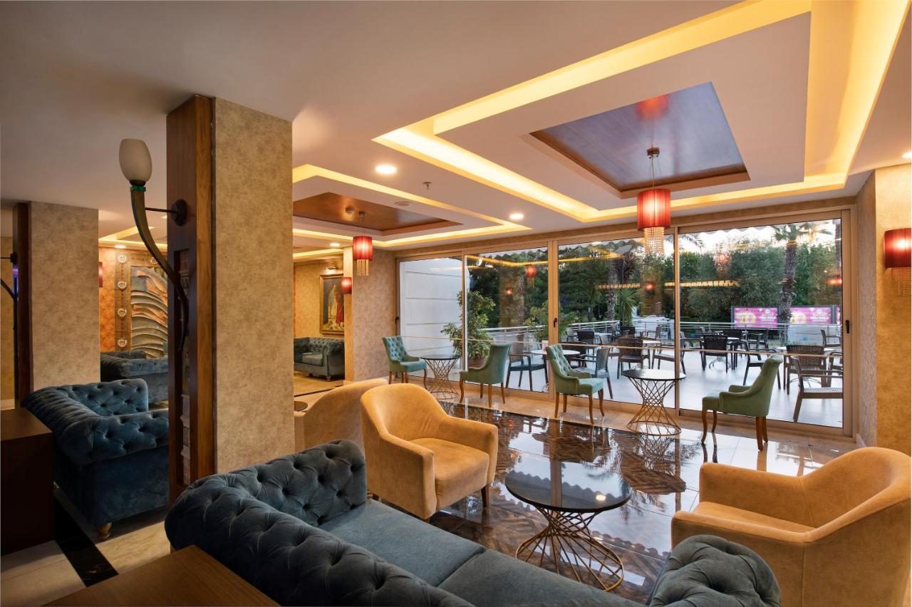 Sealife Family Resort Hotel Antalya Luaran gambar The photo shows a modern and stylish lounge or café area. It features comfortable seating arrangements with plush sofas in shades of blue and beige. The interior is well-lit with decorative ceiling lights and elegant pendant lamps hanging above. Larg