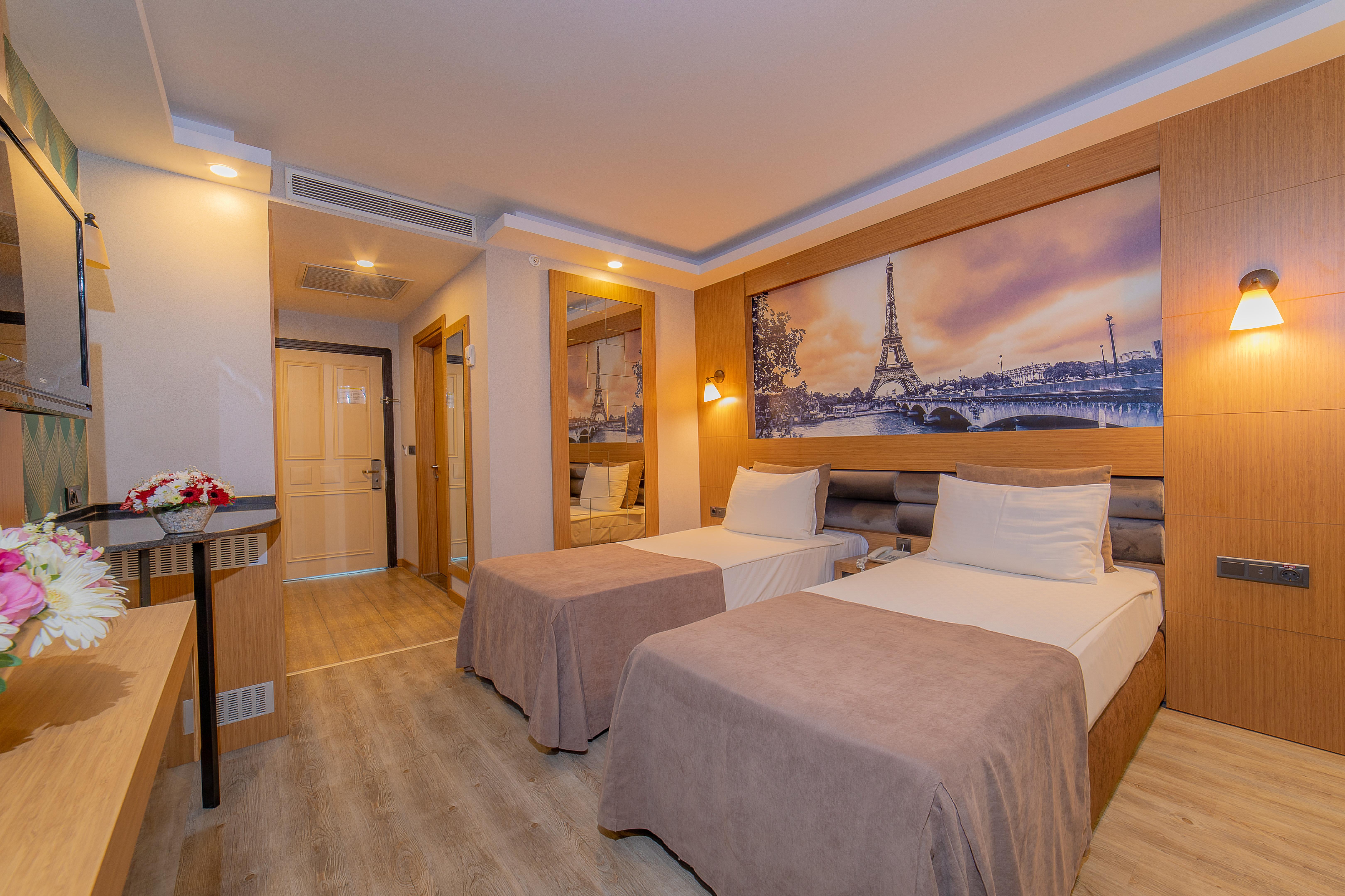 Sealife Family Resort Hotel Antalya Luaran gambar The photo depicts a modern hotel room featuring two single beds with light-colored bedspreads. The room has a warm and inviting ambiance, enhanced by the soft lighting. A large mirror is mounted on one wall, reflecting part of the room. Above the bed