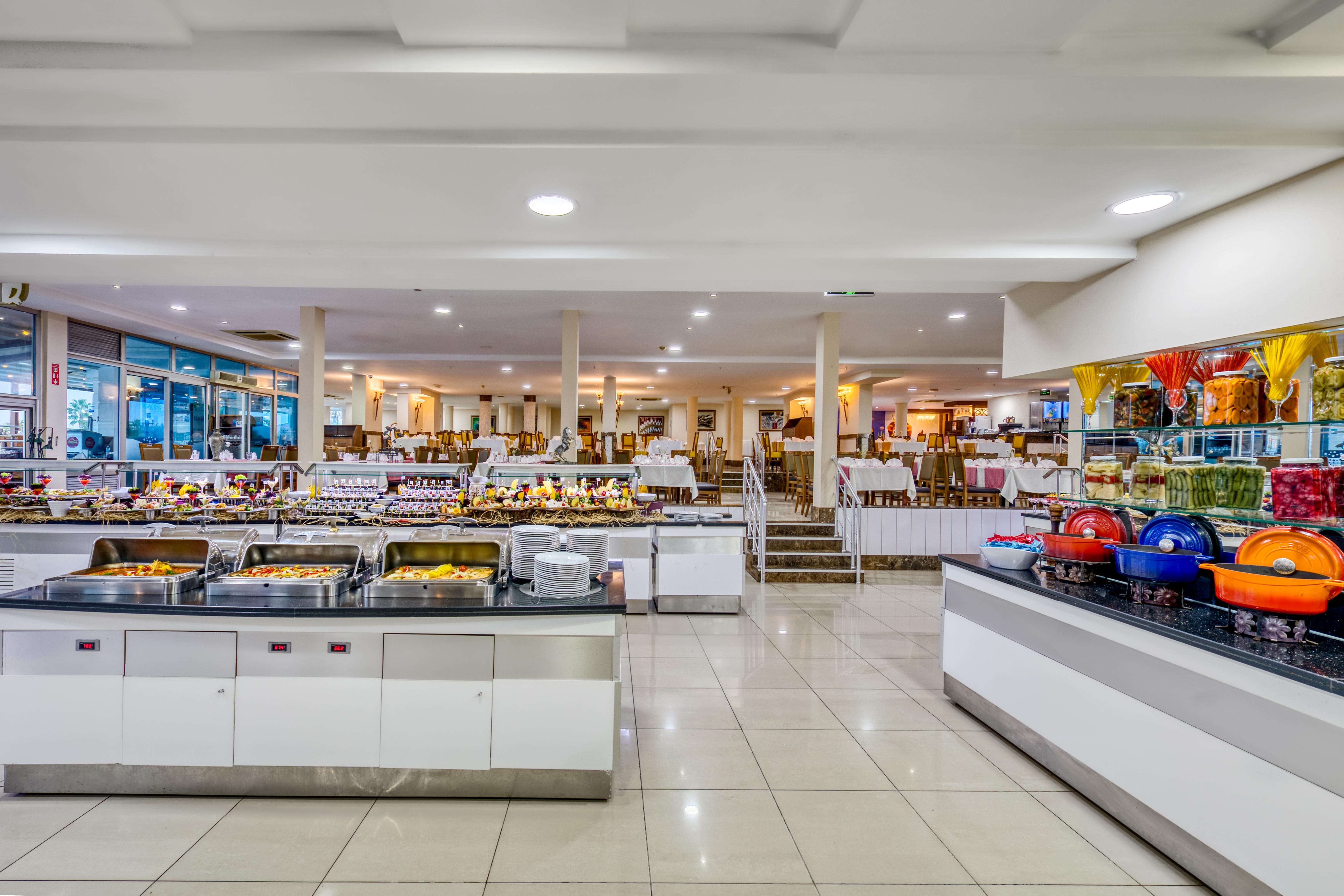 Sealife Family Resort Hotel Antalya Luaran gambar The photo depicts a spacious buffet dining area featuring several food stations. There are multiple serving counters filled with a variety of dishes, showcasing an array of foods typically found in a buffet setting. The space is well-lit, with a mode