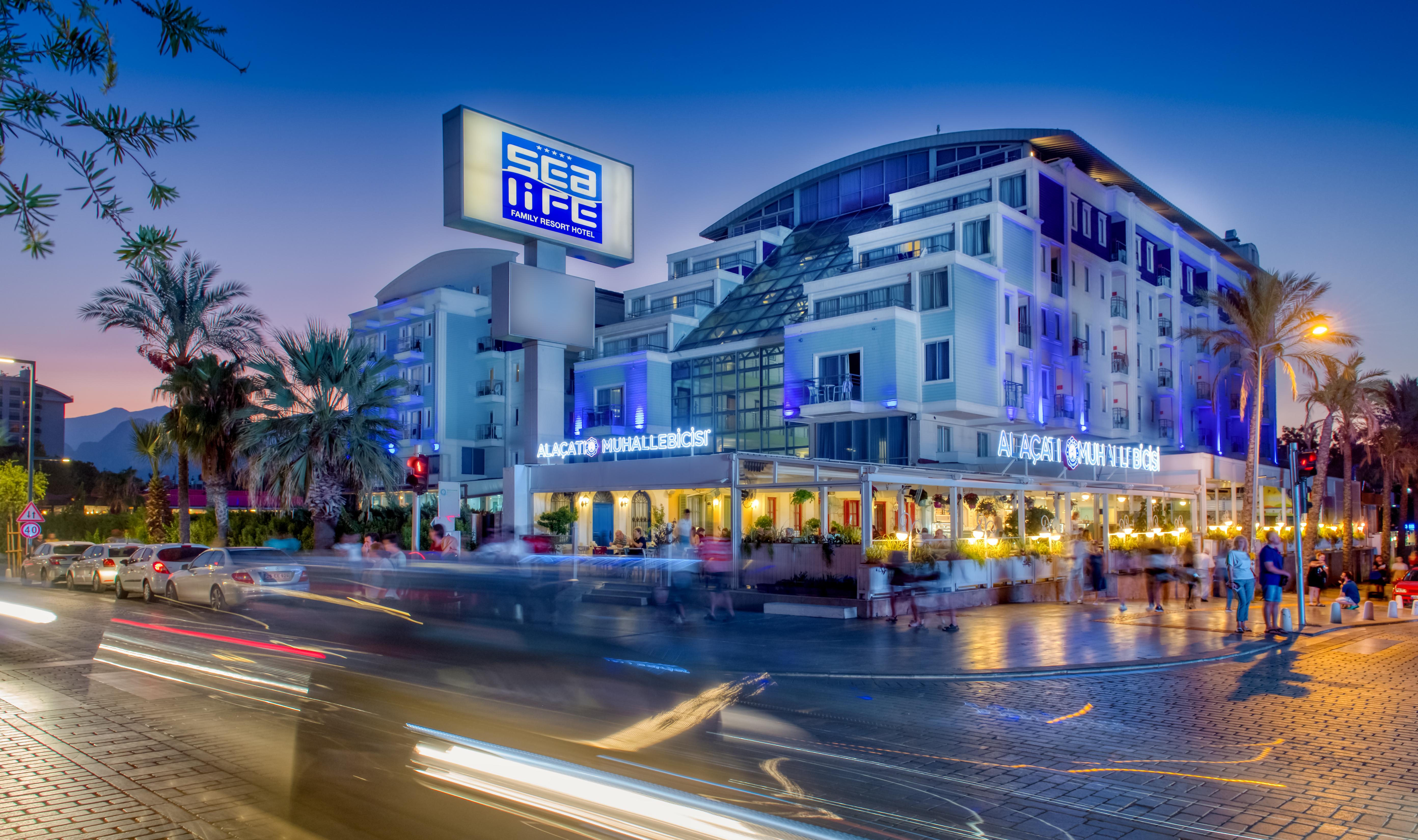 Sealife Family Resort Hotel Antalya Luaran gambar The photo shows a modern building with a prominent sign that reads "Sea Life." The structure has multiple stories and a sleek, contemporary design, featuring large windows. In front of the building, there appears to be a restaurant with outdoor seati