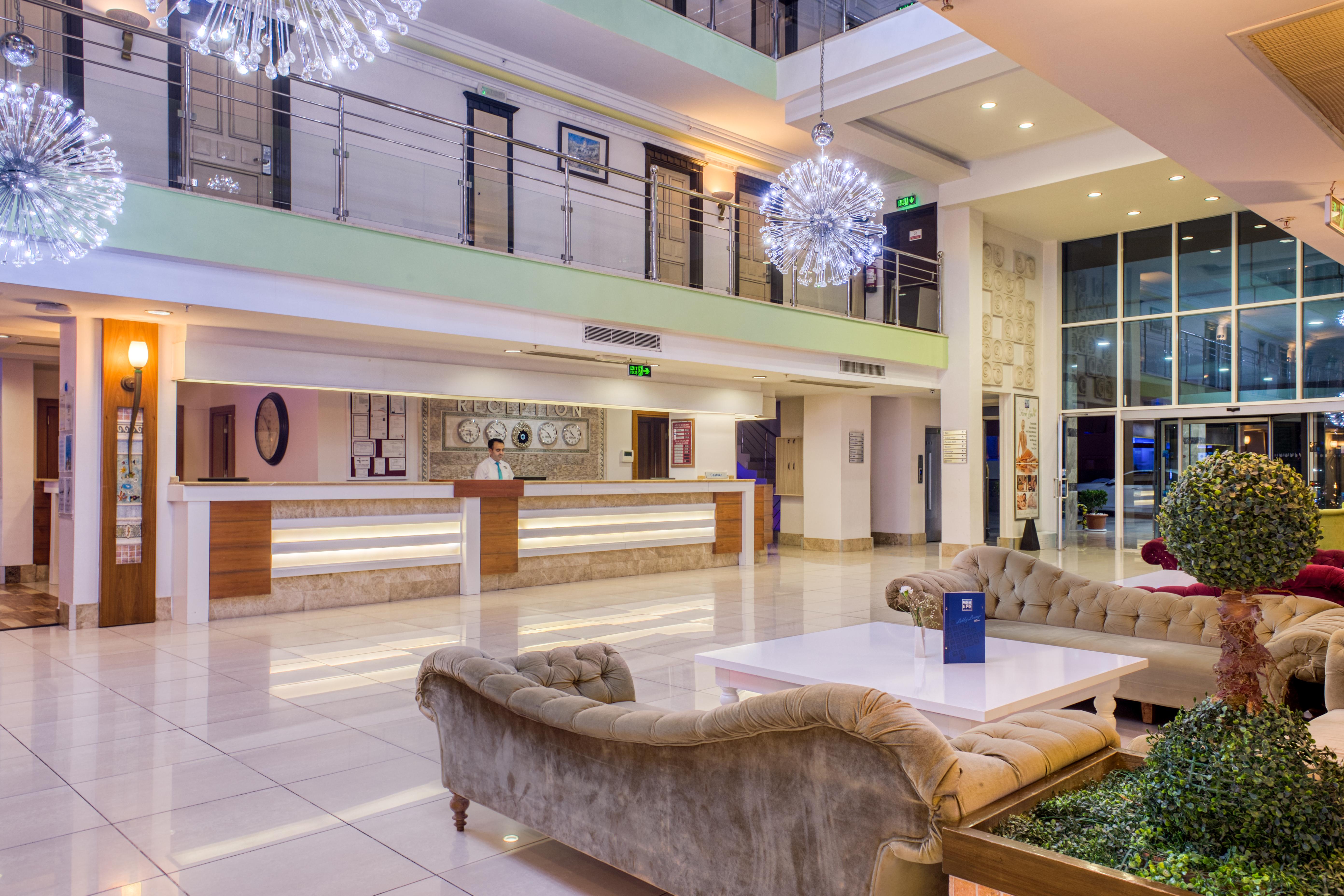 Sealife Family Resort Hotel Antalya Luaran gambar The photo depicts a modern hotel lobby. The space features a spacious and stylish design with large windows allowing natural light to enter. There is a reception desk in the background, along with some decorative elements on the walls. The seating ar