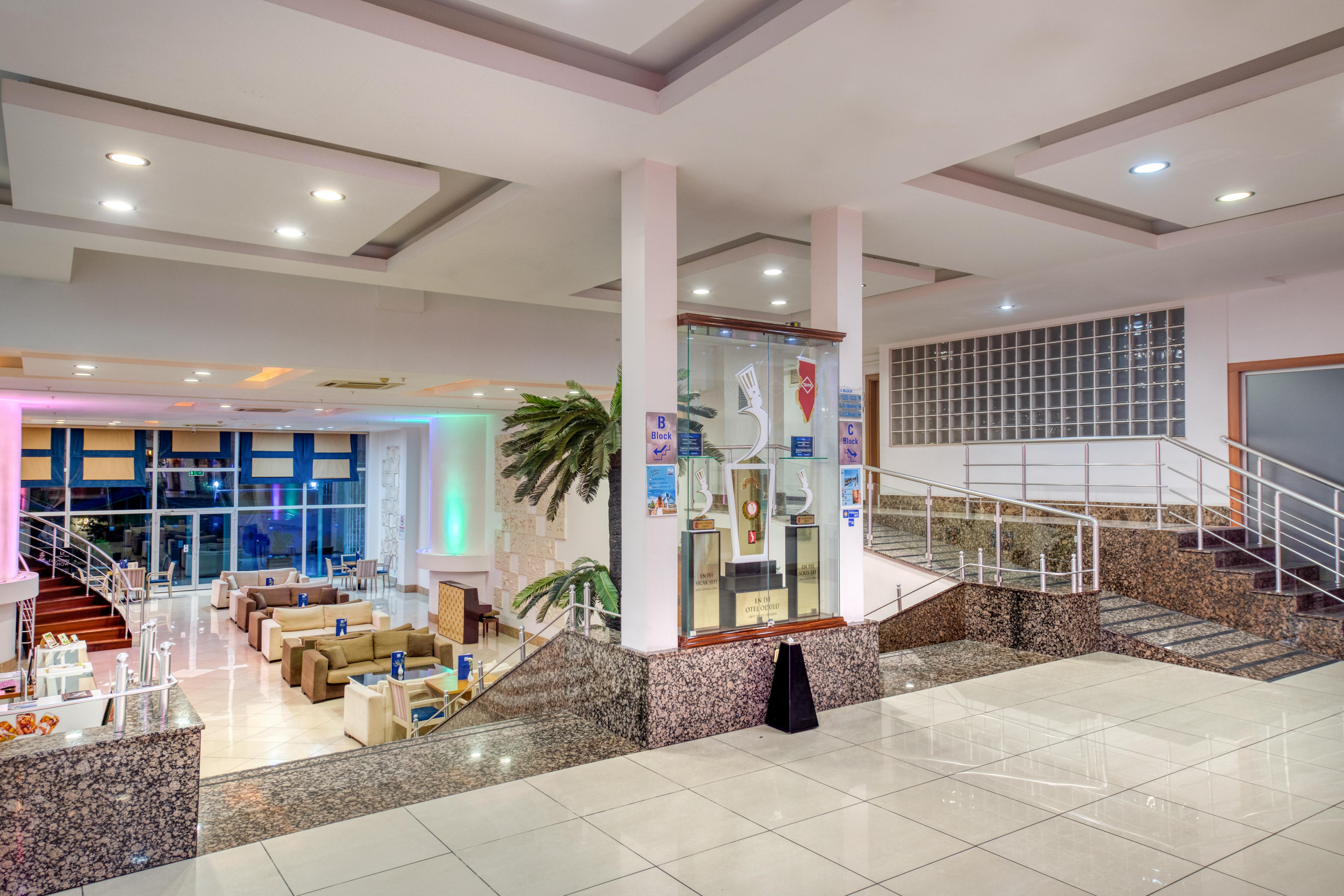 Sealife Family Resort Hotel Antalya Luaran gambar The photo shows a spacious indoor area, likely a hotel or a public building, featuring a modern design. There are several seating arrangements with comfortable couches and chairs visible in the background. The space is well-lit, with ambient lighting