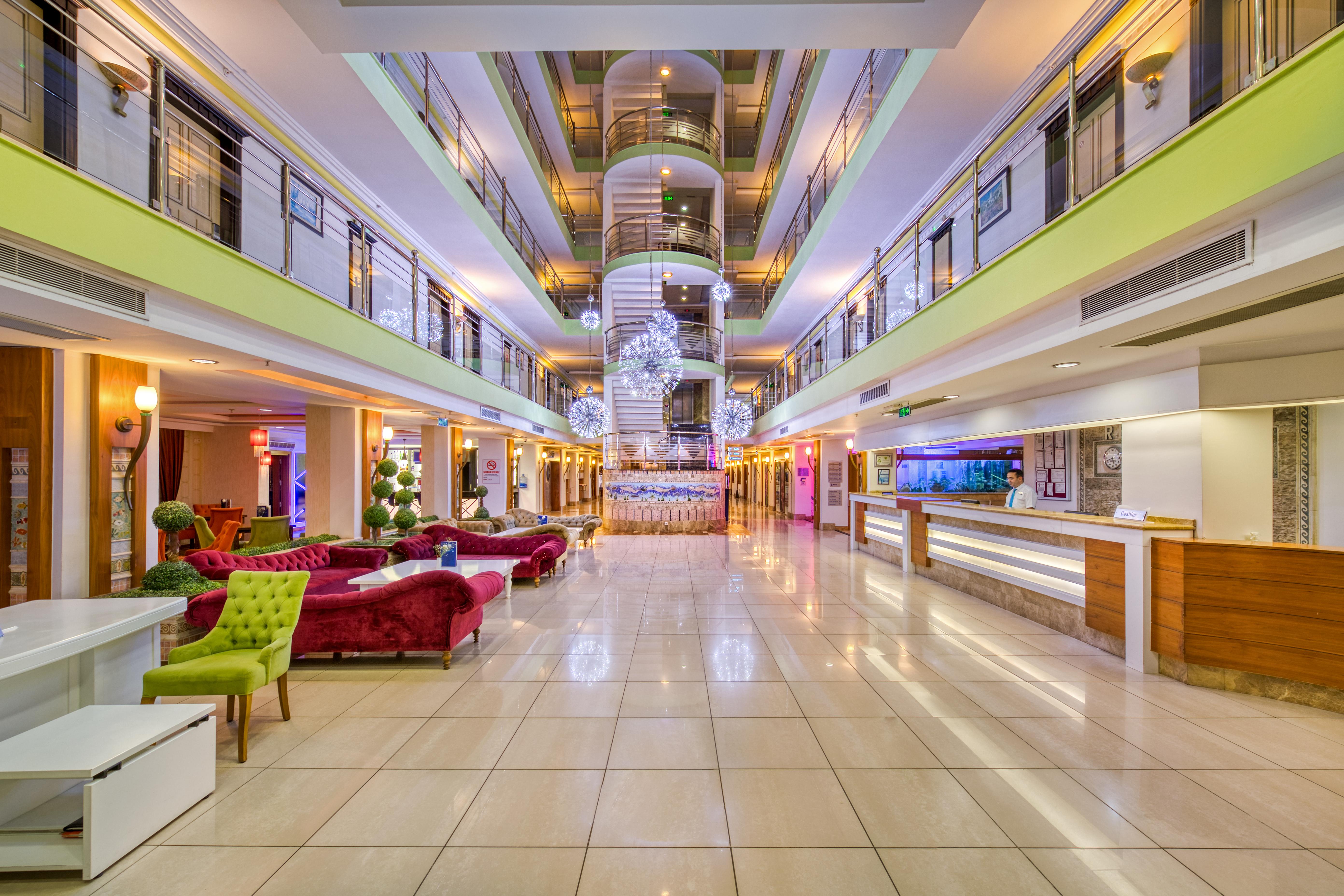 Sealife Family Resort Hotel Antalya Luaran gambar The photo shows the interior of a modern hotel lobby. It features a spacious design with a polished tile floor and various seating areas. Elegant sofas in vibrant colors, such as red and green, are arranged tastefully. In the center, there is a strik