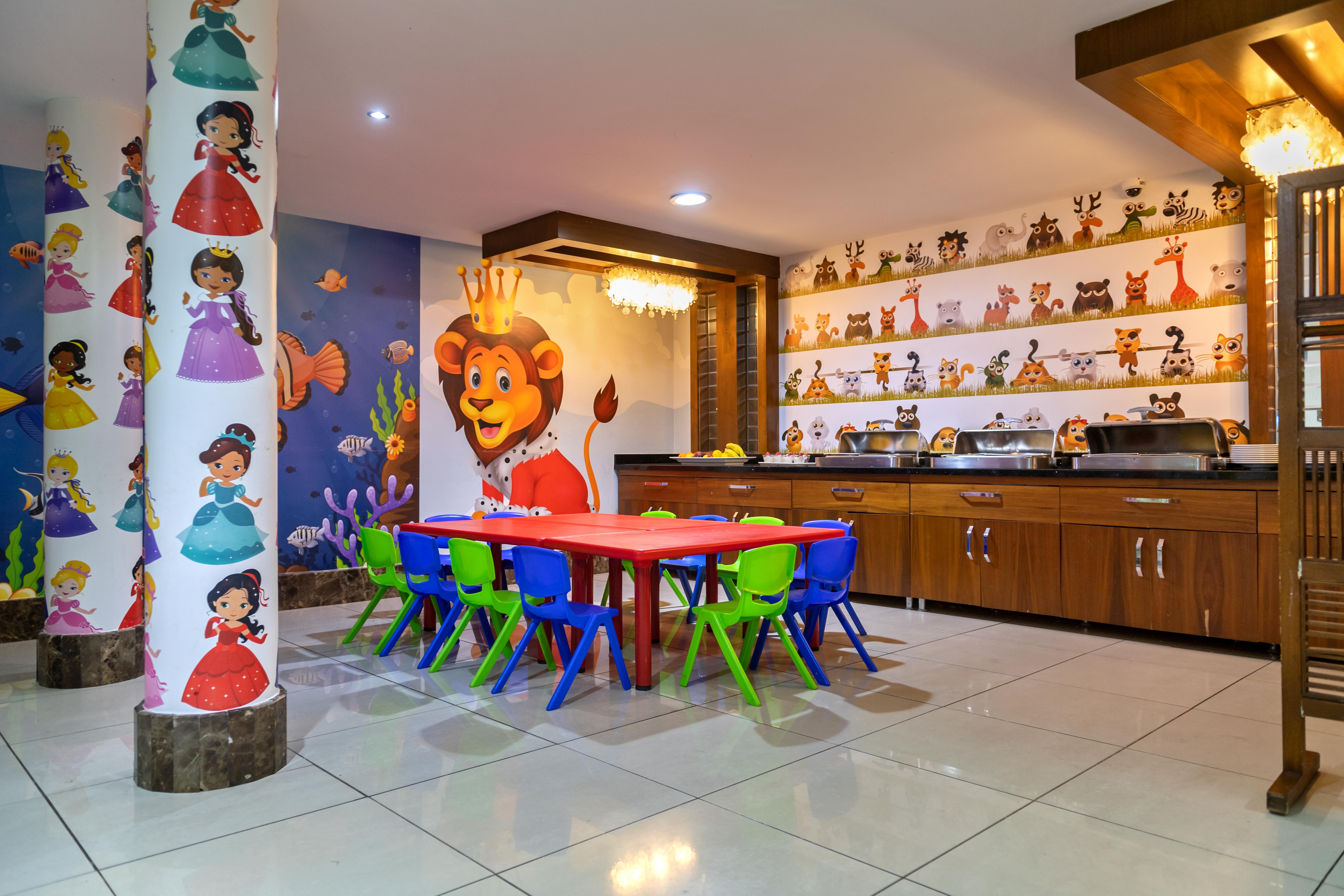 Sealife Family Resort Hotel Antalya Luaran gambar The photo shows a vibrant children's playroom or activity area. There is a red table surrounded by small chairs in various colors (blue and green). The walls are decorated with colorful murals, including images of cartoon characters, animals, and pri