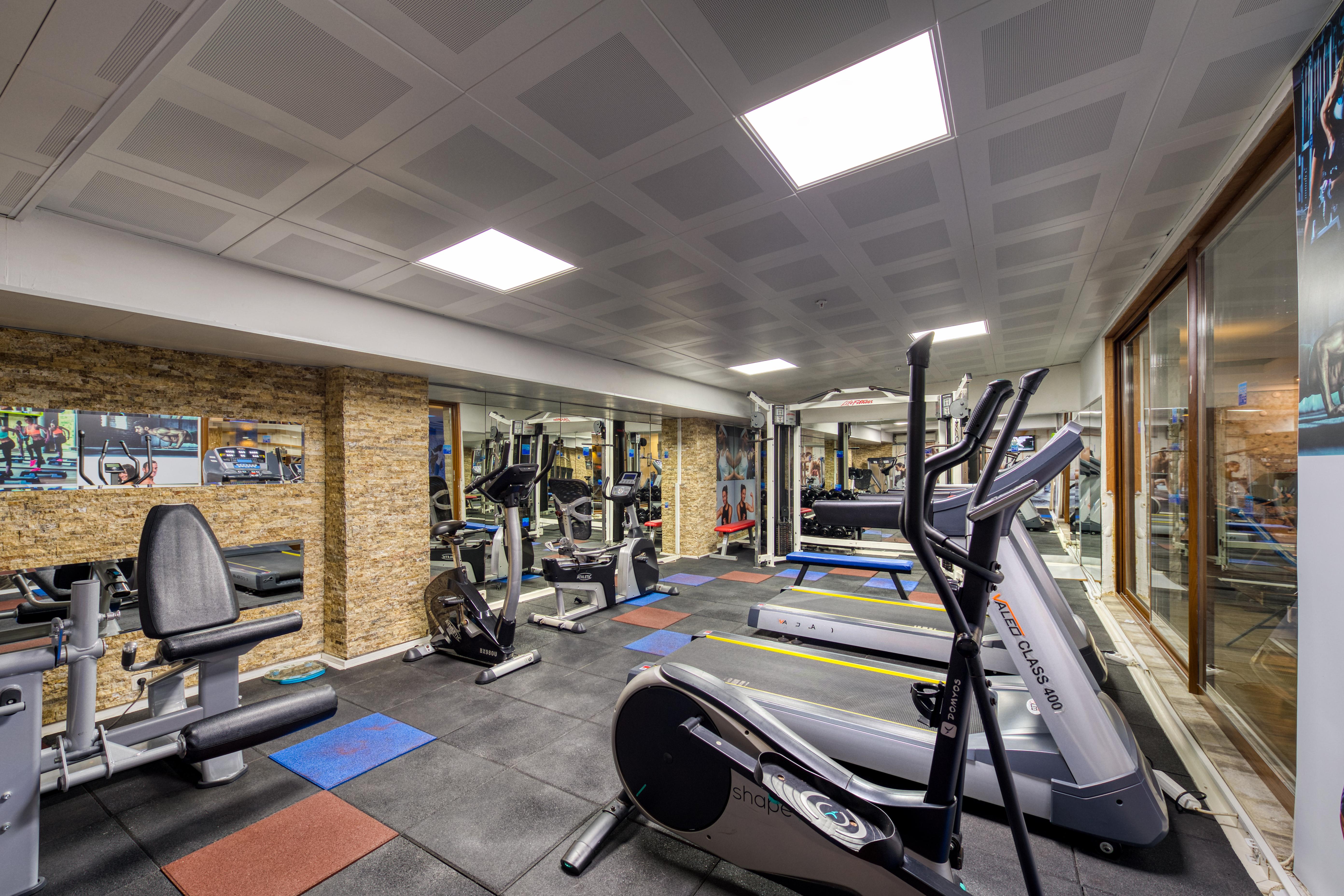Sealife Family Resort Hotel Antalya Luaran gambar The photo shows an indoor gym space equipped with various exercise machines. There are cardio machines like treadmills and an elliptical trainer, along with strength training equipment. The flooring is made of black mats, and there are a few colored 
