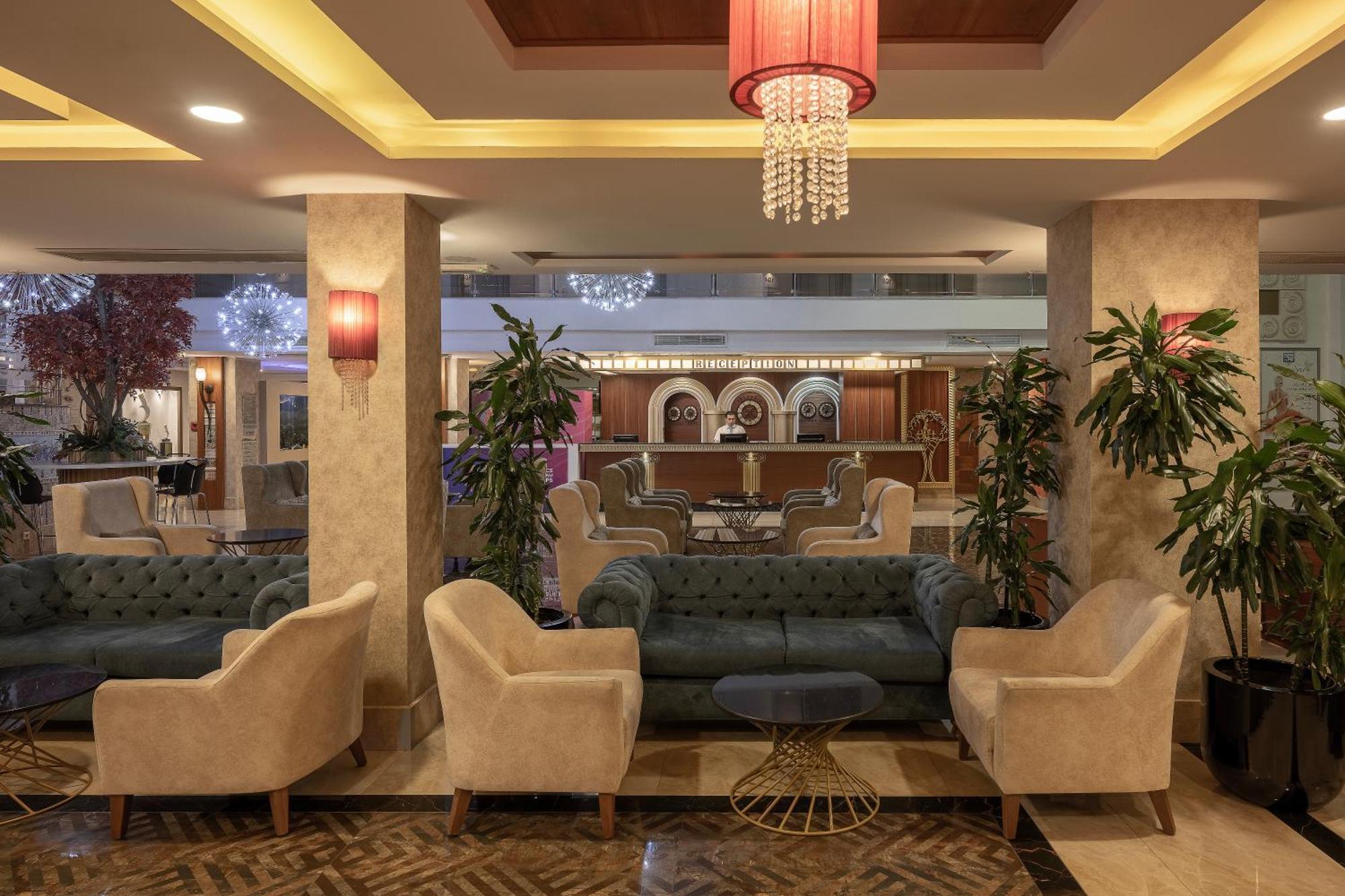 Sealife Family Resort Hotel Antalya Luaran gambar The photo shows a stylish and elegant lobby area, featuring comfortable seating arrangements. There are several plush armchairs and a large sofa, which have a mix of light and dark colors. The space is well-lit with ambient lighting, including decora