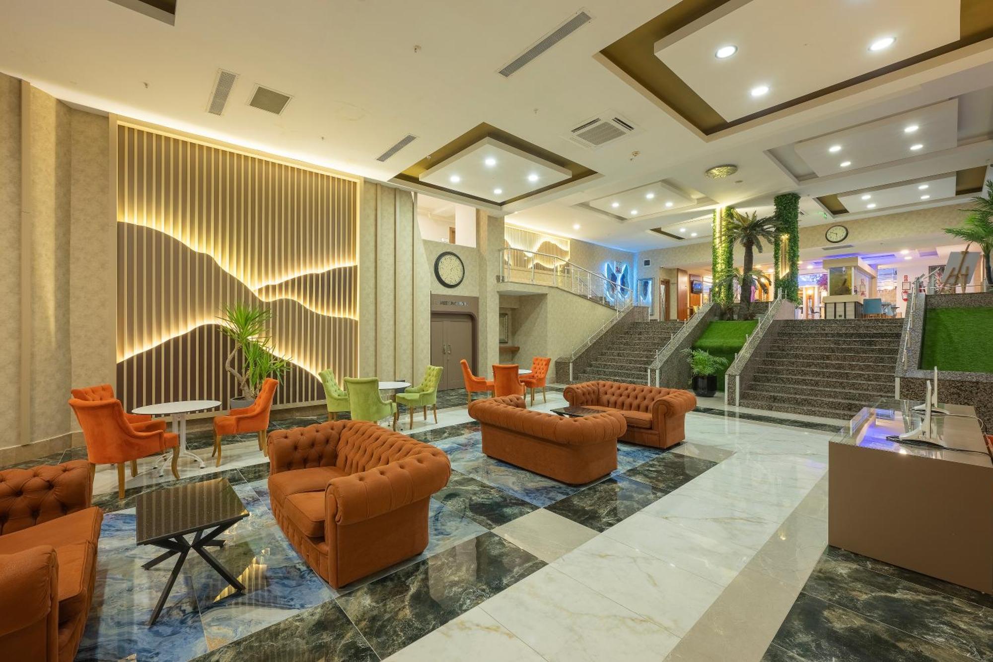 Sealife Family Resort Hotel Antalya Luaran gambar The photo depicts a spacious, modern lobby area within a hotel or similar establishment. The floor features a striking design with dark and light marble patterns. There are several comfortable seating arrangements, including orange upholstered sofas 