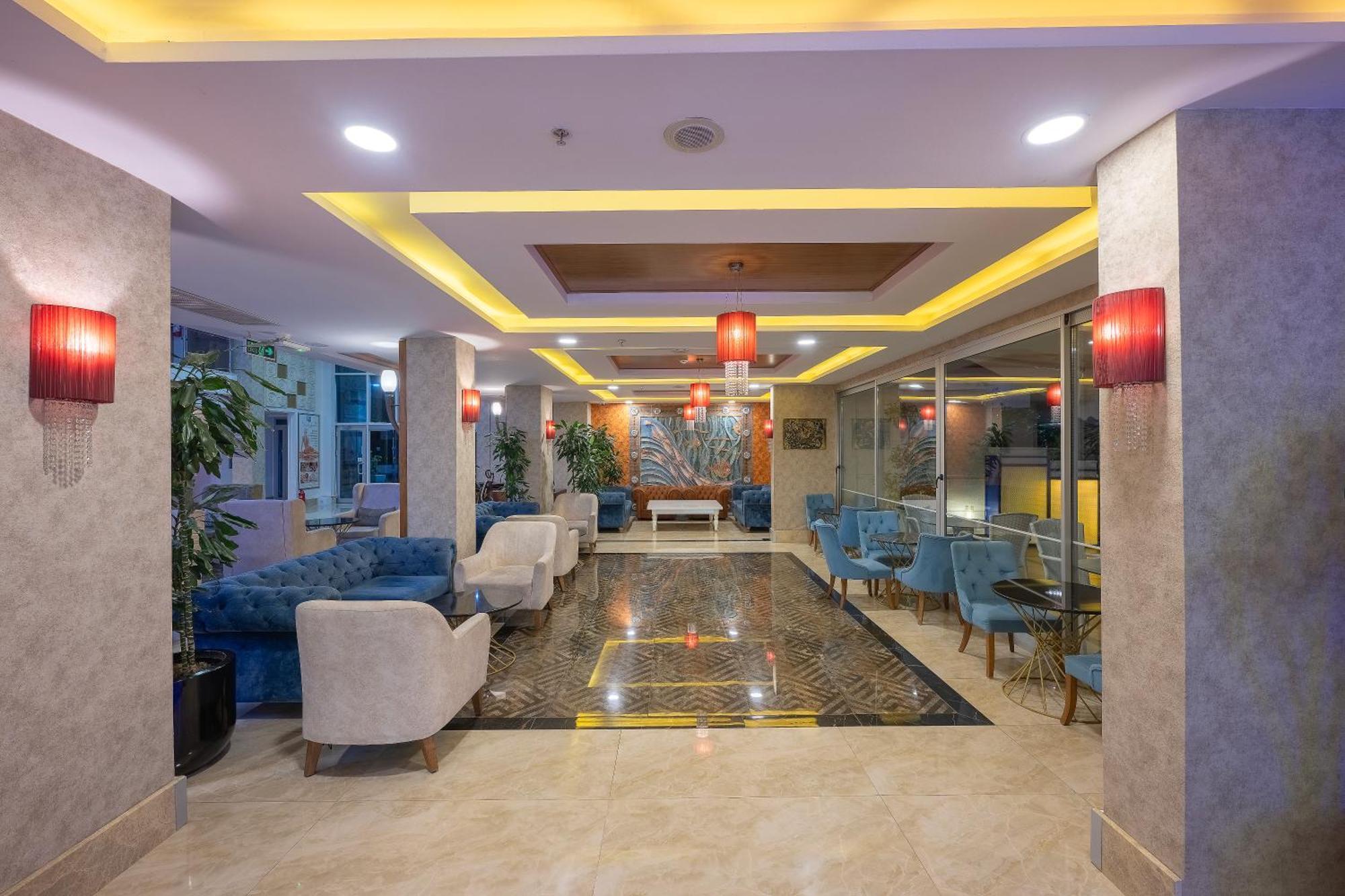 Sealife Family Resort Hotel Antalya Luaran gambar The photo shows a modern lobby area, characterized by stylish decor and a welcoming atmosphere. There are comfortable seating arrangements with blue upholstered chairs and white armchairs. The flooring appears to be a polished stone, complemented by 
