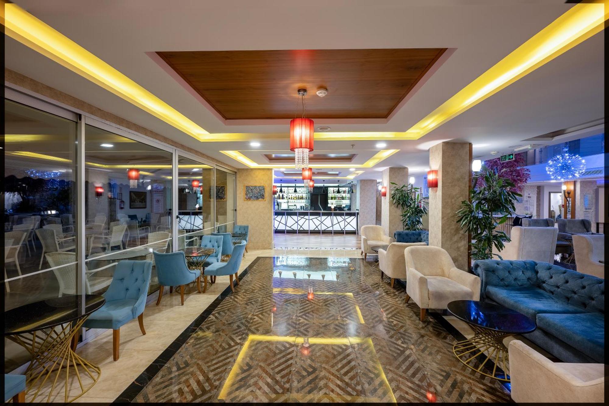 Sealife Family Resort Hotel Antalya Luaran gambar The image shows a stylish interior of a lounge or hotel lobby. There are several comfortable seating areas with blue and white chairs. The floor is designed with a patterned tile that complements the modern decor. In the background, there is a bar ar