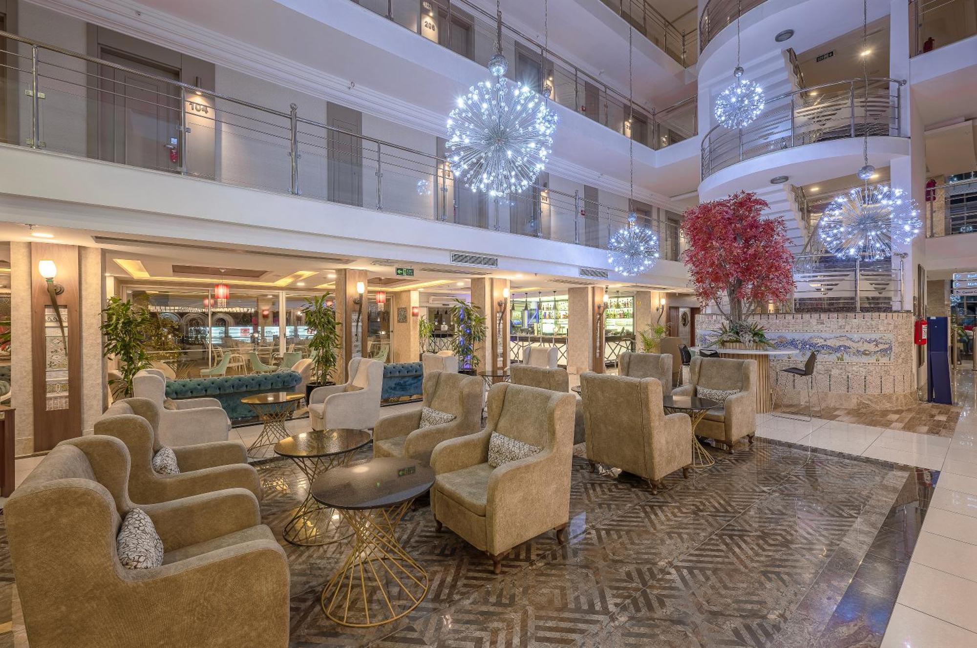 Sealife Family Resort Hotel Antalya Luaran gambar The photo depicts a modern hotel lobby with a stylish and inviting atmosphere. It features a seating area furnished with plush, beige armchairs arranged around a round glass table. The floor boasts an elegant patterned design. 

In the background, th