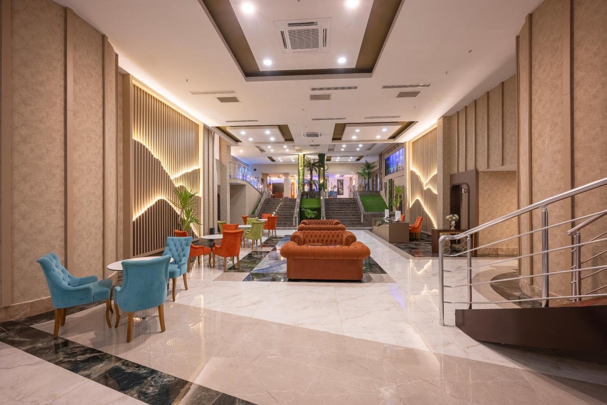 Sealife Family Resort Hotel Antalya Luaran gambar The photo shows a modern lobby area of a hotel or building. The space is spacious, featuring a mix of lighting and decorative elements. There are elegant furnishings, including an orange sofa and colorful chairs in blue and orange. The floor is made 